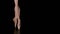 Graceful legs of a ballerina in white pointe shoes. Ballerina shows classic ballet pas. Shot in a darkness on spotlights