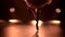 Graceful legs of a ballerina in white pointe shoes. Ballerina shows classic ballet pas. Shot in a darkness on spotlights