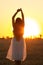 Graceful silhouette figure of young woman walking in field at sunset, beautiful romantic girl with long hair outdoors