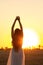 Graceful silhouette figure of young woman walking in field at sunset, beautiful romantic girl with long hair outdoors