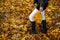 Graceful woman feet in elegant boots walking on fall leaves in an autumn forest