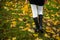 Graceful woman feet in elegant boots walking on fall leaves in an autumn forest