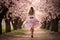 Graceful woman with long skirt walking in beautiful blooming cherry blossom woods with pink petals in Spring.