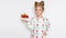Gracious little girl with blond hair and blue eyes standing on a white background wearing a sweatshirt and a strawberry