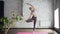 Gracious young woman is doing yoga practicing tree pose Vriksasana during individual class in wellness center. Green