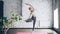 Gracious young woman is doing yoga practicing tree pose Vriksasana during individual class in wellness center. Green