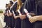 Graduate concept.Cropped image of row of students in black robes with diplomas in hands at graduation ceremony