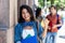 Graduate female student happy about exam with friends in background in front of university building