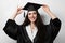 Graduate girl with master degree in black graduation gown and cap on white background. Happy young woman careerist have