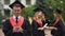 Graduate students standing in park, young man with smartphone looking at camera