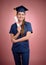 Graduated nurse in blue uniform in graduation cap standing and holding a scroll by her hands