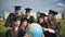 Graduates in black robes examine a geographical globe sitting on the grass.