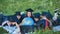 Graduates in black robes looking at a georgraphic globe lying on the grass.