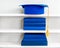 Graduation blue mortarboard on top of stack of books on wooden shelf