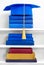 Graduation blue mortarboard on top of stack of books on wooden shelf