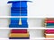 Graduation blue mortarboard on top of stack of books on wooden shelf