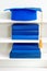 Graduation blue mortarboard on top of stack of books on wooden shelf