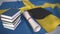 Graduation cap, books and diploma on the Swedish flag. Higher education in Sweden related conceptual 3D animation