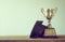 graduation cap with champion golden trophy on wood table with co