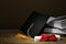 Graduation hat, books and diploma on wooden table against brown background, space for text