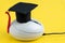 Graduation hat on computer mouse on solid yellow background using as online course, e-learning or internet study via website and
