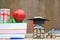 Graduation hat on the glass bottle and banknote on the textbook, Saving money for education concept