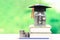 Graduation hat on the glass bottle and books on natural green ba