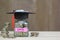 Graduation hat on glass bottle with Stack of coins money on wood