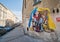 Graffiti by Chemis artist depicts a little girl hiding a European fairy tale character under a blanket from Ukrainian flag