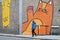 Graffiti of large cats outside of `Kitty CafÃ©` in Spaniel Row street with unfocused man with blue coat walking by.