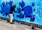 Graffiti painter paiting a wall with blue fish cartoon pictures of several fishes in Taolin in Estonia. Eastern European artist.
