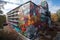 graffiti sprayer artist creating intricate, colorful mural on abandoned building