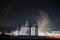 Grain dryer plant working at night.  Floating steam around. Agro farm metal elevator, tall silos with dark  sky on the background.