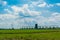 Grain elevator in a green field. The blue cloudy sky. Agricultural business. Trucks go to the loading. Spring. Young green plants.