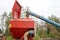Grain from the pipe falls into a large, red seeding unit, a combine with large wheels for plowing the land, a device for sowing gr