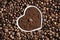 Grain of roasted coffee in a cup in the form of a heart in a pile of coffee beans, background.