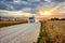 Grain truck on a rural road next to a rye field at sunset