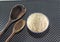 Grains of cereal rice on a dark background in a jar next to wooden spoon