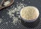 Grains of cereal rice on a dark background in a jar next to wooden spoon