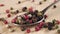 Grains of colored assorted dried spicy peppers fall into a spoon on a wooden background