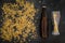 Grains of malting barley near beer bottle on black background top view