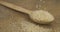 Grains of rice fall into a wooden spoon. Seeds fall out of a full spoon onto burlap. Food abundance concept