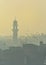 A grainy picture of a minaret of a mosque on a foggy morning with pigeons flying