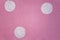 Grainy pink wall with three white circles. rough surface texture