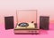 Gramophone record player from sixties with speakers. Turntable for single vinyl with pink bottom with light pink background