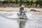 Gramsh, Albania - July 30, 2019. Moto biker crossing the river with splashing water