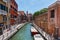 Grand Canal in Venice with boats and gandules docket motor boat near the bridge. Colorful residential house and small bridges