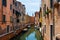 Grand Canal in Venice with boats and gandules docket motor boat near the bridge. Colorful residential house and small bridges