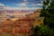 Grand Canyon South Rim framed by evergreen trees - showing layers of rock that go on forever under early evening sky