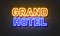 Grand hotel neon sign on brick wall background.